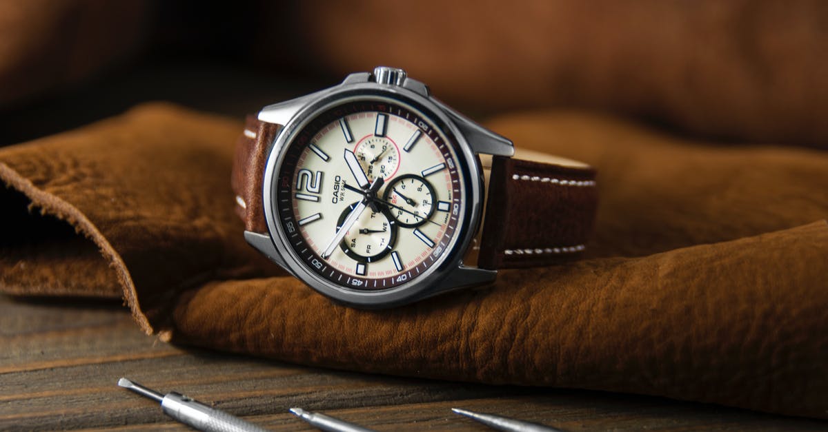 Is the time on the 100$ bill actually fixed? - Stylish round wristwatch with chronograph and brown strap placed on leather material near repair tools in modern workshop