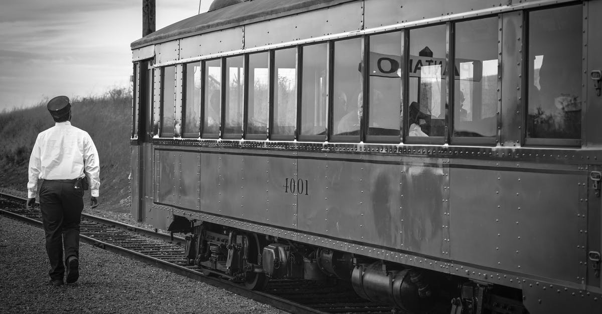 Is the train conductor a time traveler? - Greyscale Photography of Train Beside Woman