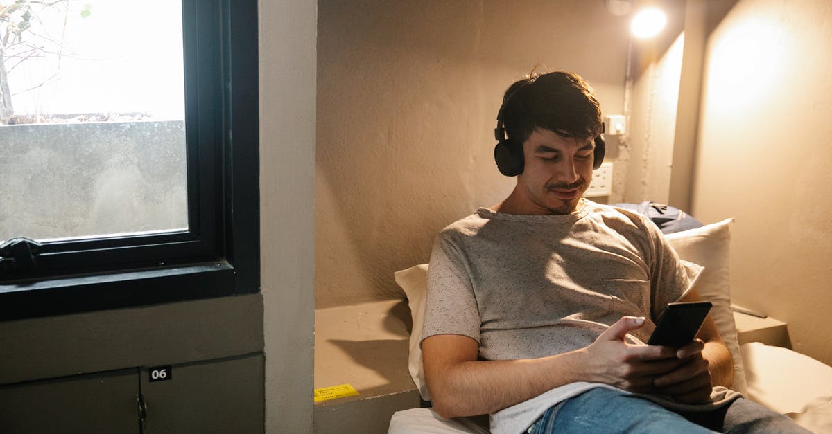 Is the train conductor a time traveler? - Smiling man resting on bed and using smartphone and headphones