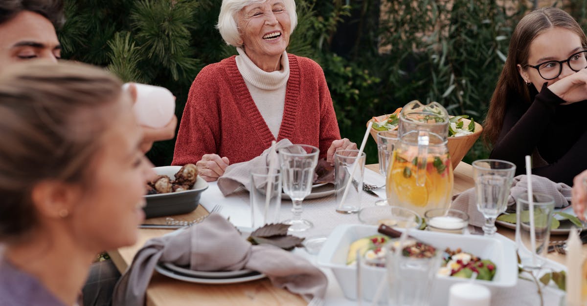 Is there a precedent for Girl Meets World? - Smiling elderly woman with family and friends enjoying dinner at table backyard garden