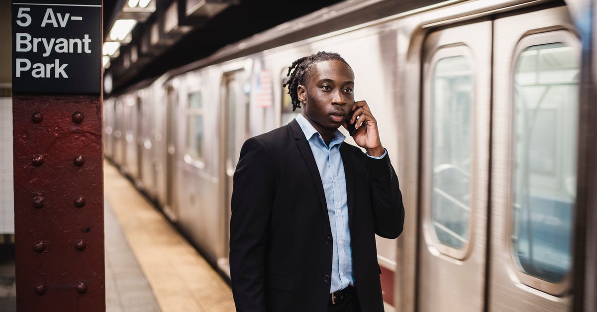 Is there an alternate version of "Duel" where the truck stands waiting for the guy after the train has passed by? - Serious African American male in formal suit talking on smartphone while waiting for underground train to stop