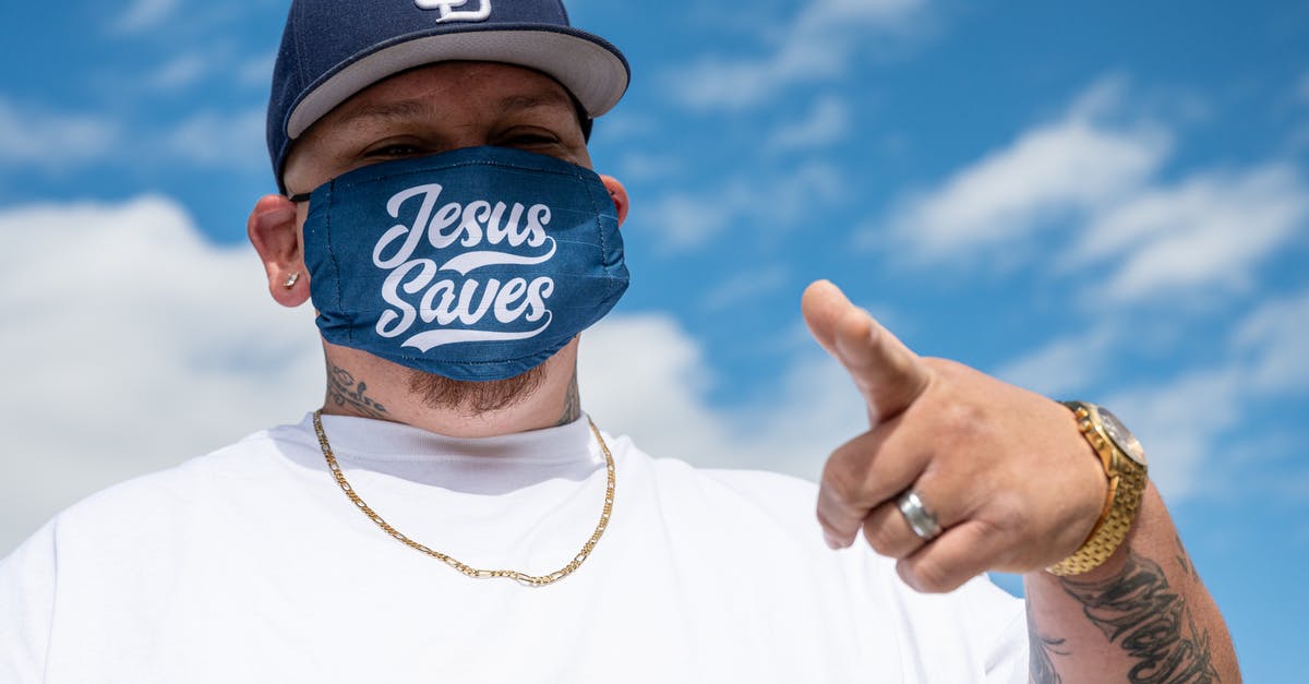 Is there any further significance to Russell's tattoo? - Ethnic man with tattoos in white t shirt and cap and protective mask with Jesus Saves inscription pointing finger at camera