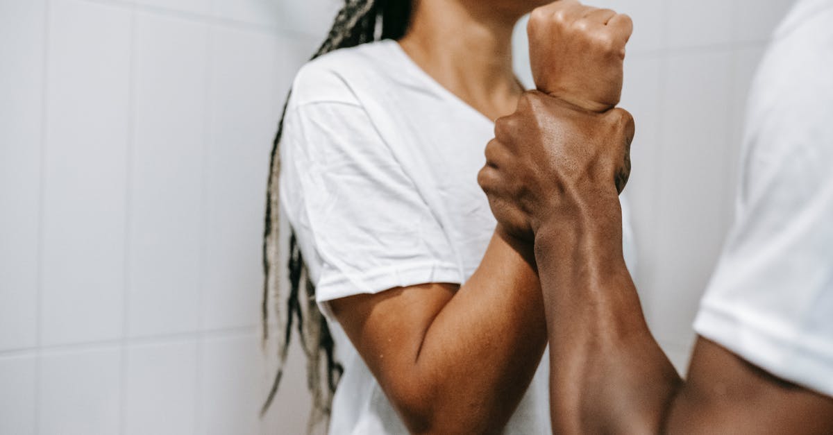 Is there any mention of this conflict and fight in original stories? - Side view of crop unrecognizable aggressive African American male holding wrist of scared wife while quarreling together in bathroom