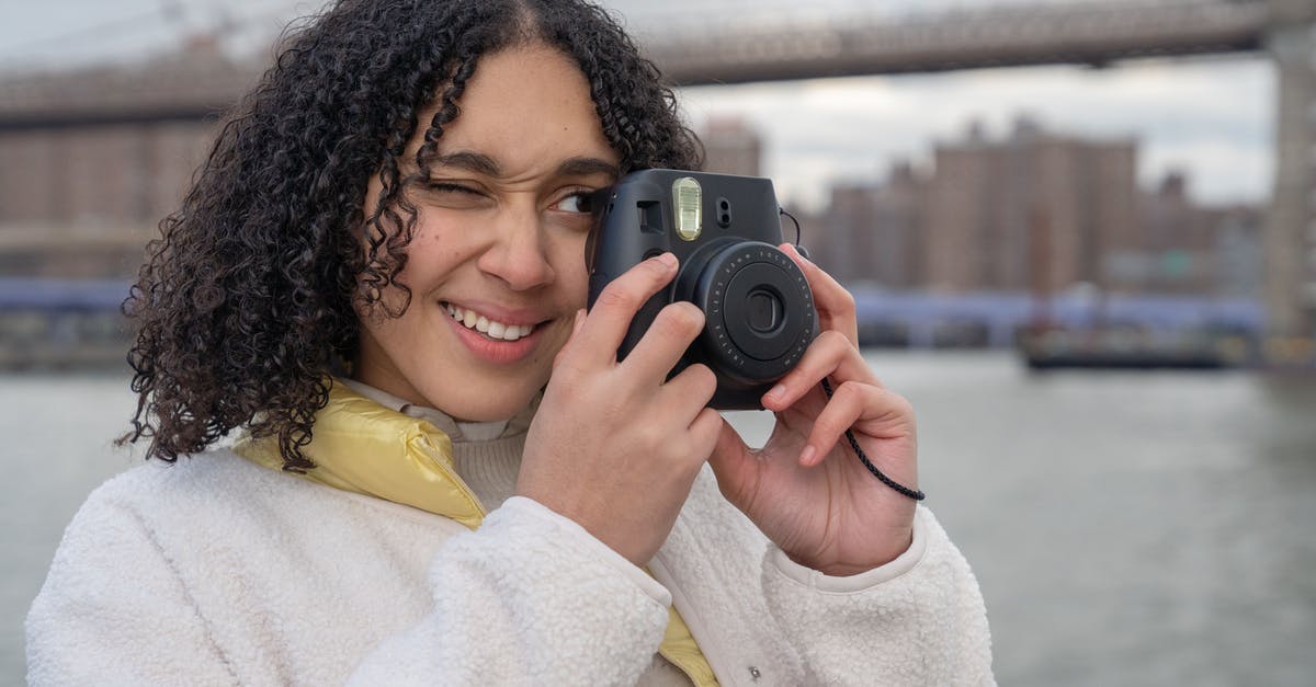 Is there any use in obliviating the town with rainfall after photographs have been taken? - Hispanic female photographer with photo camera near river and bridge