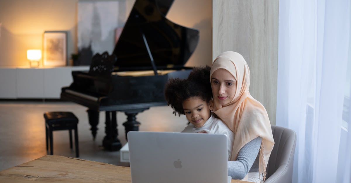 Kids movie about a kleptomaniac girl with a fear of fire and an abusive piano teacher [closed] - Friendly Muslim mother sitting with little African American daughter on knees and watching cartoon on portable laptop in cozy apartment