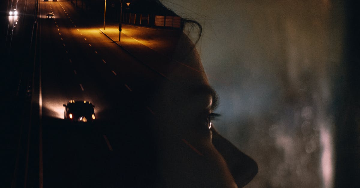 Last scene of taxi driver - Side view crop female sitting in car behind window glass reflecting road with moving cars and street lights at night