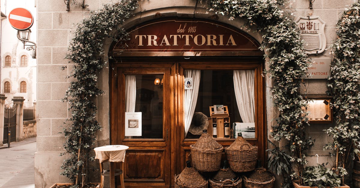 Location of Vector's hideout - Exterior of cozy Italian restaurant with wooden door and entrance decorated with plants