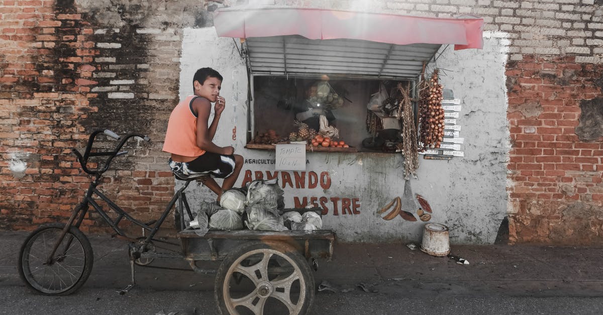 Locational origins of Radnor - Ethnic boy sitting on aged tricycle near poor street stall