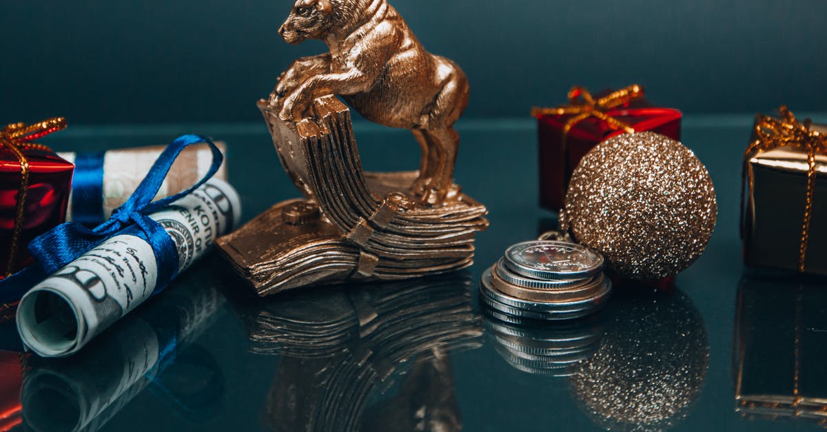 Mention of "crackers" in Zodiac - High angle composition of Ox year symbol figurine and wrapped presents placed on mirrored table with coins and rolled and tied dollar banknotes