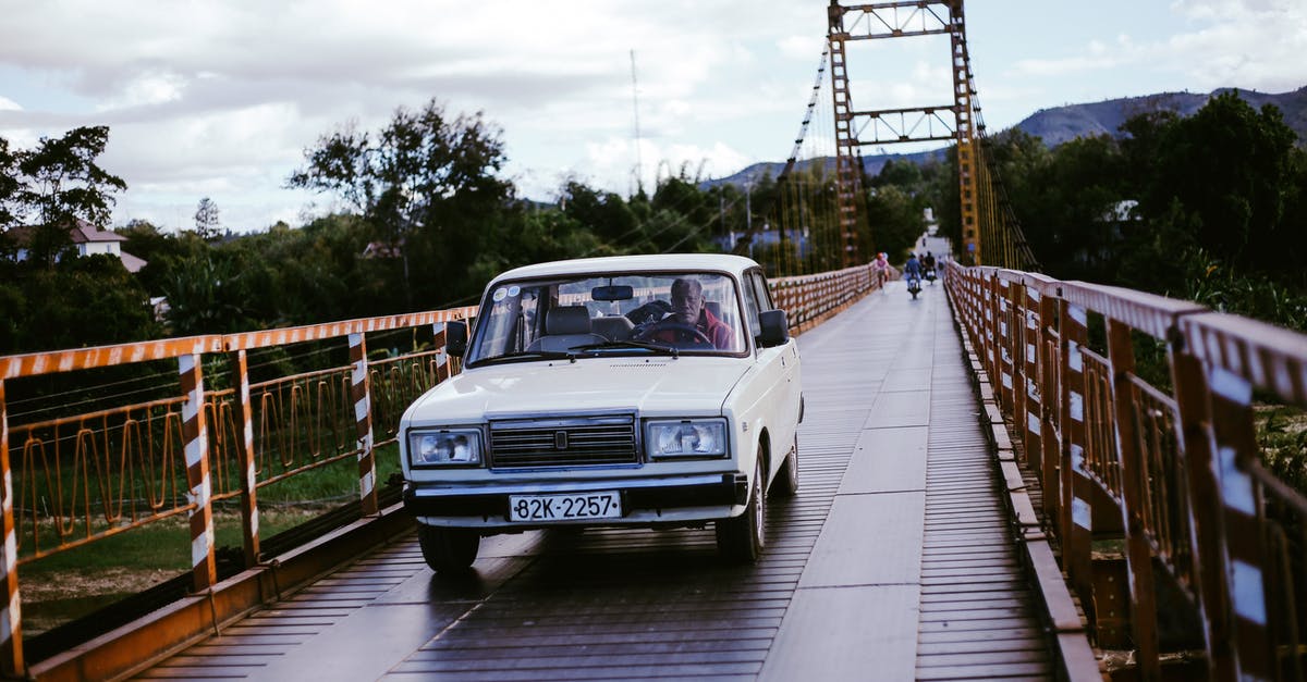 Monks know how to drive a car? - Man Driving White Car on Bridge