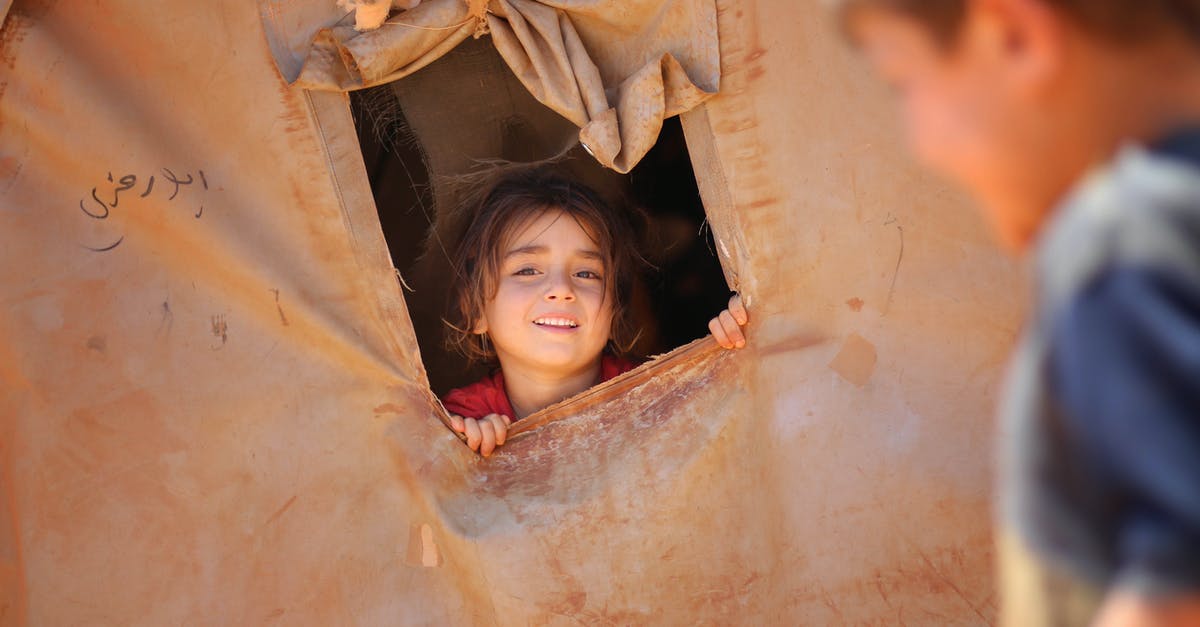 Motive behind kidnapping homeless kids in Gotham - Smiling little ethnic girl looking out of window in tent