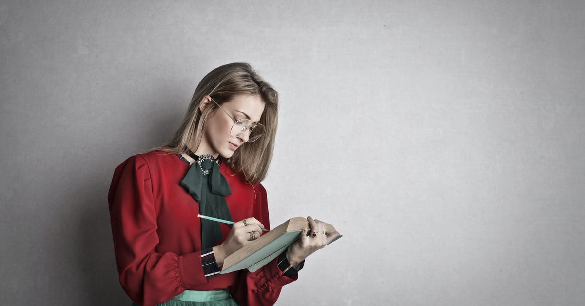 Movie about a girl who wishes or writes in a book for things to happen to people? [closed] - Pensive attentive woman in glasses and elegant vintage outfit focusing and taking notes with pencil in book while standing against gray wall