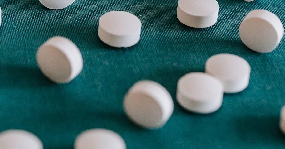 Movie asking the scientist what should be the color of the pill they have developed, deciding on orange/purple? [closed] - Closeup of similar round white pills spilled on green tissue in random order