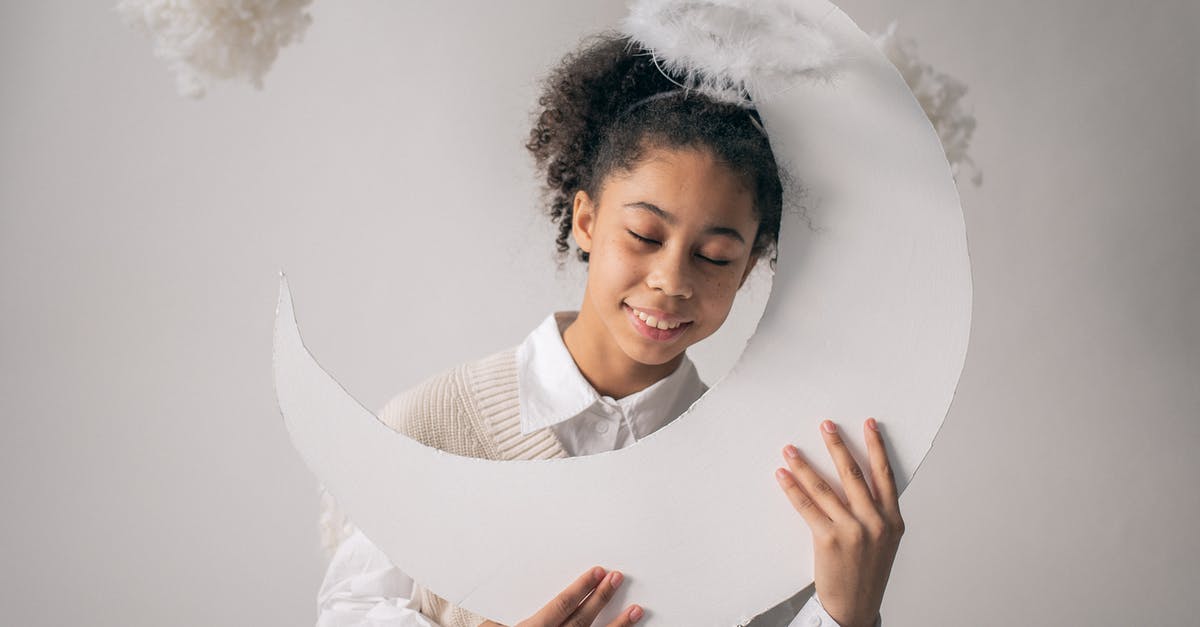 Movie trailer: Kidnapped little girl shooting herself with handgun [closed] - Smiling African American girl in white outfit and nimbus holding white paper moon on white background with cotton in studio
