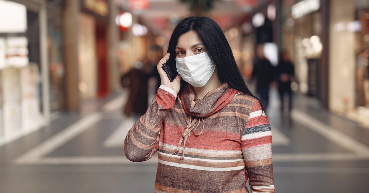 Movie where the main character is waiting all his life for a phone call [closed] - Worried casual female wearing protective mask and looking at camera while answering phone call against blurred background in city center during coronavirus pandemic