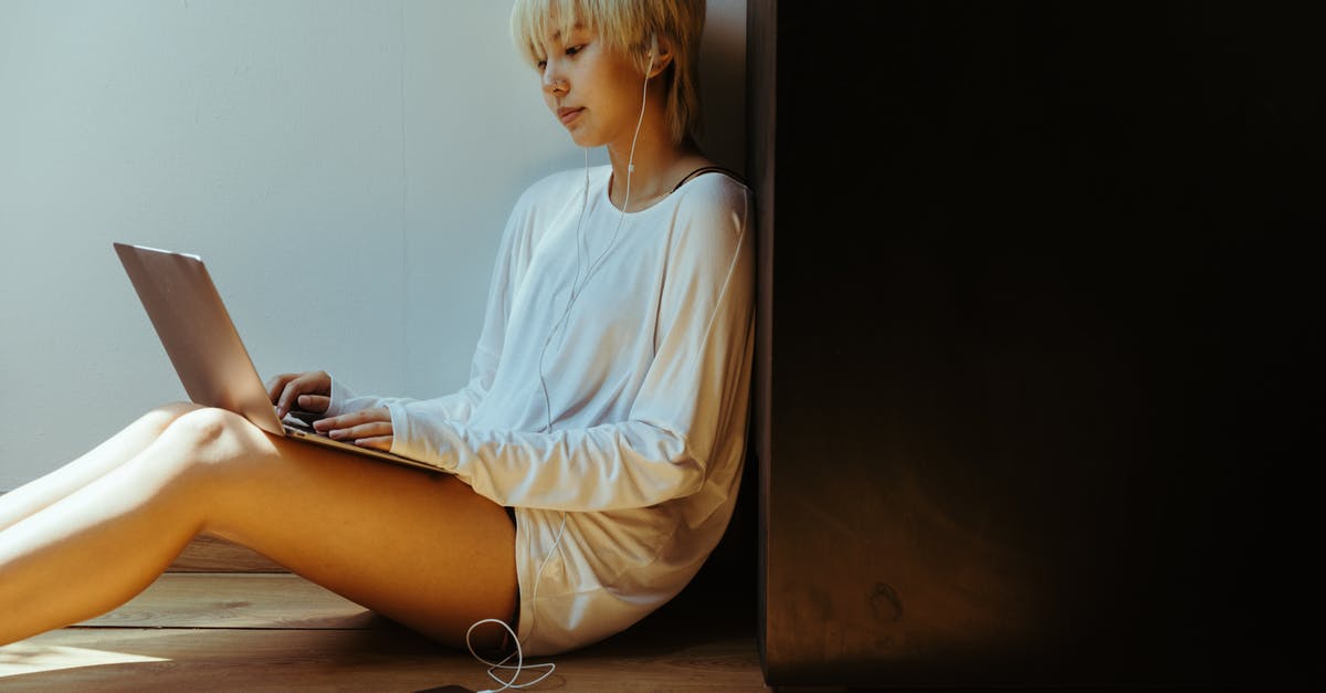 music used in The Social Network AND Moneyball [closed] - Side view of young female remote employee in casual wear and earphones listening to music while surfing internet on netbook and sitting on floor leaned on wall in sunlight