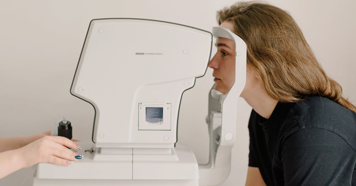 Not using the obvious test to proof RoboCop's superiority over pure machines? - Side view of crop anonymous doctor checking eyesight of female patient using vision screening device in clinic