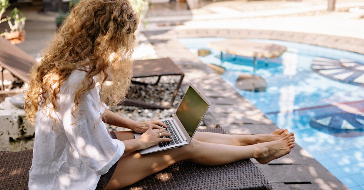 Not using the obvious test to proof RoboCop's superiority over pure machines? - From above side view of unrecognizable barefoot female traveler with curly hair typing on netbook while resting on sunbed near swimming pool on sunny day