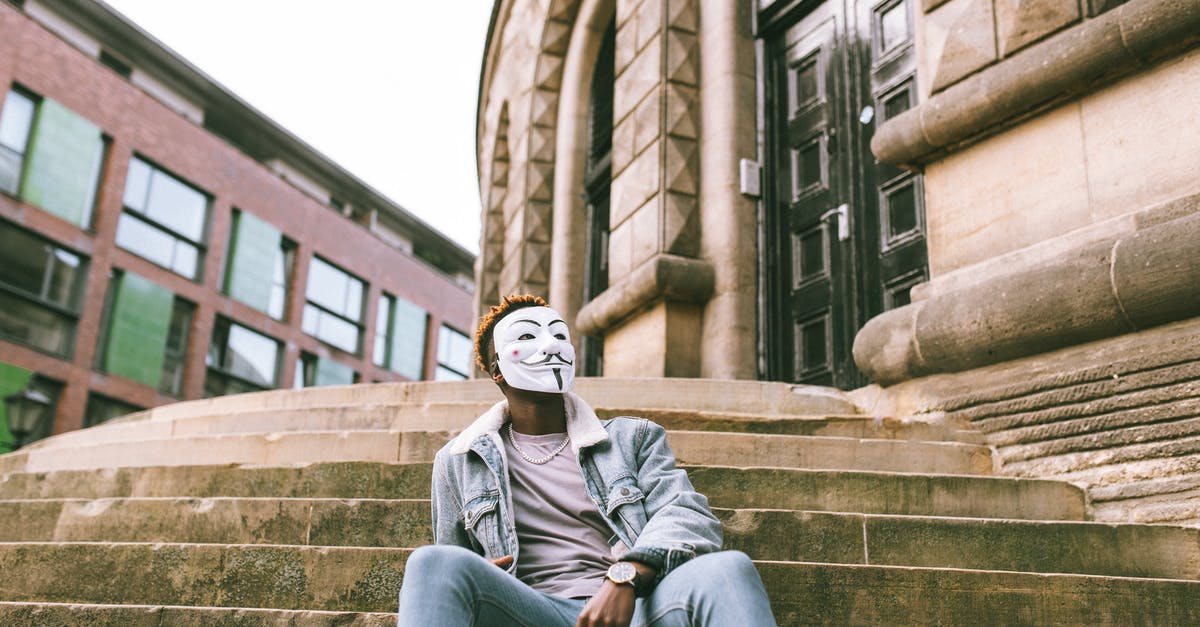 Old comedy/spy movie where the heroine is a much better fighter than the leading man [closed] - Unrecognizable African American male rebel in casual wear and anonymous mask sitting on old building staircase in town