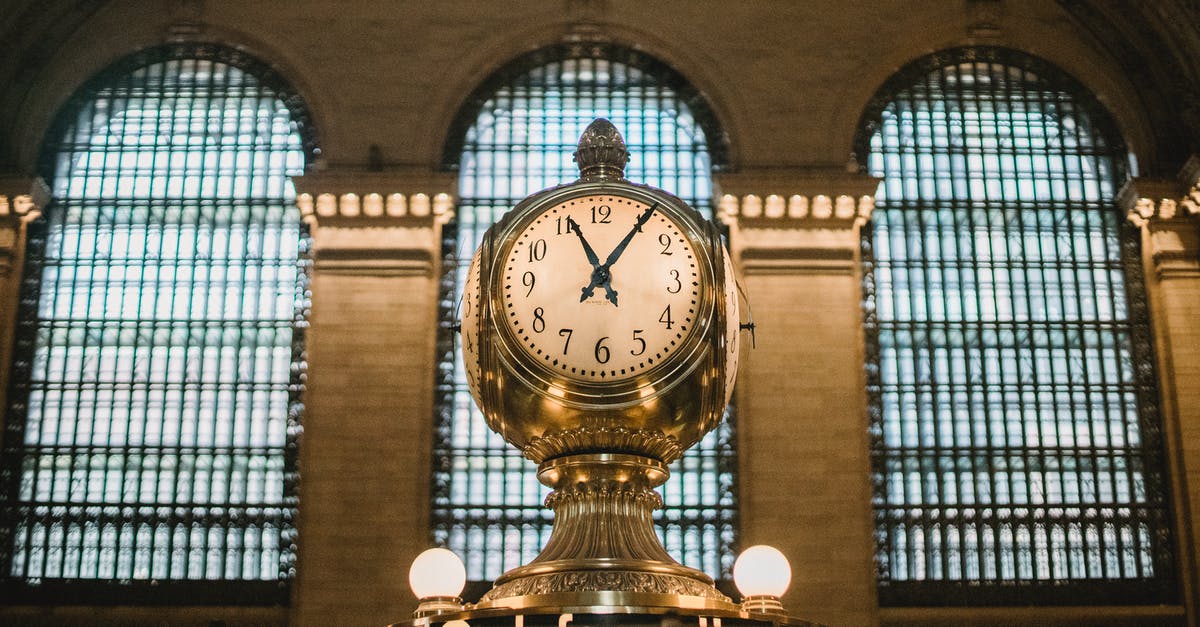 Once Upon A Time In America denoumente - From below of aged retro golden clock placed atop information booth of historic Grand Central Terminal with arched windows