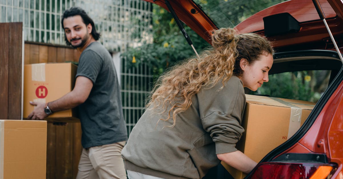 Origin of Aliens in 'A Quiet Place'? - Positive multiethnic boyfriend and girlfriend unloading car trunk during moving to new home in quiet green yard on summer day