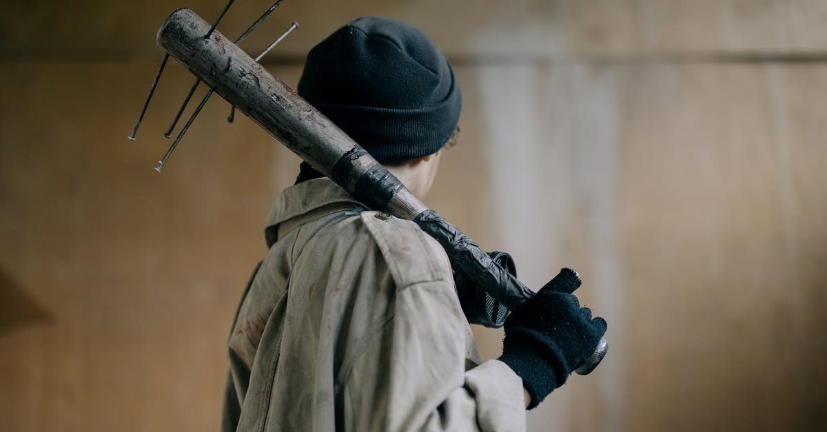 Paradox in Back to the future II? - Person in Black Knit Cap and Beige Coat Holding Brown Wooden Stick