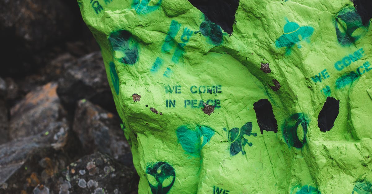 Prometheus to Alien: Who is on the crashed spaceship in Alien? [duplicate] - Big rock with colorful green paint and words we come in peace near alien faces placed near rough stones in countryside in daylight