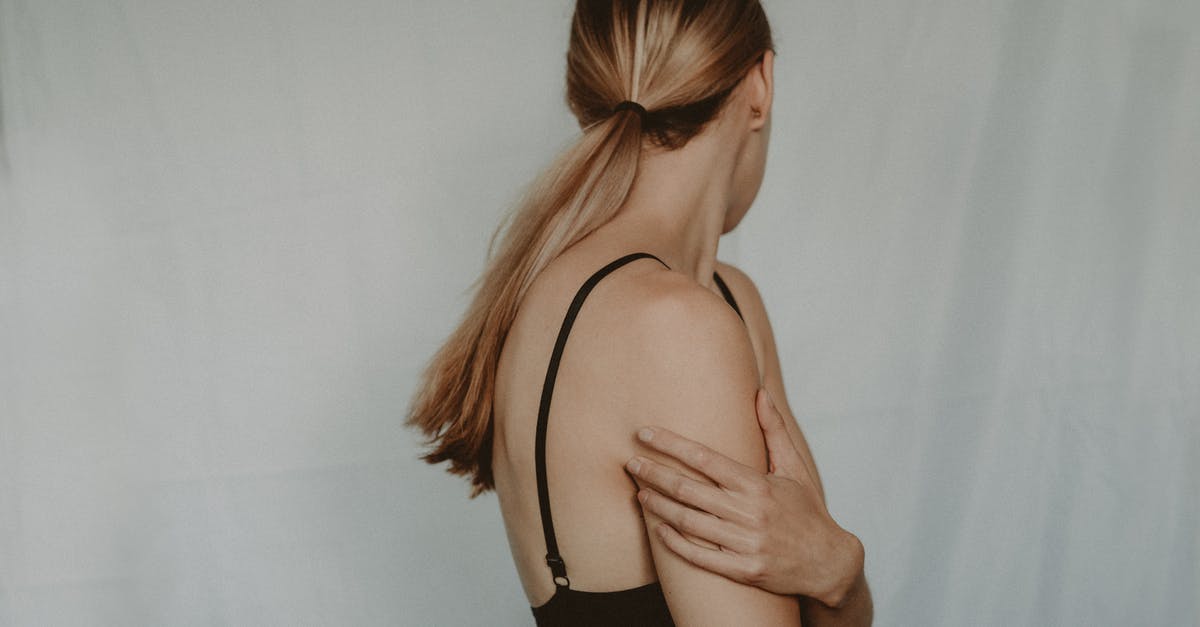 Psychological abuse in Parasite? [closed] - Side view of unrecognizable young female with long hair and black bra standing near grey wall turning head away
