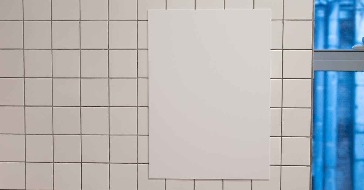 Public address announcements in OITNB - Blank white placard hanging on wall covered with white tiles inside of building