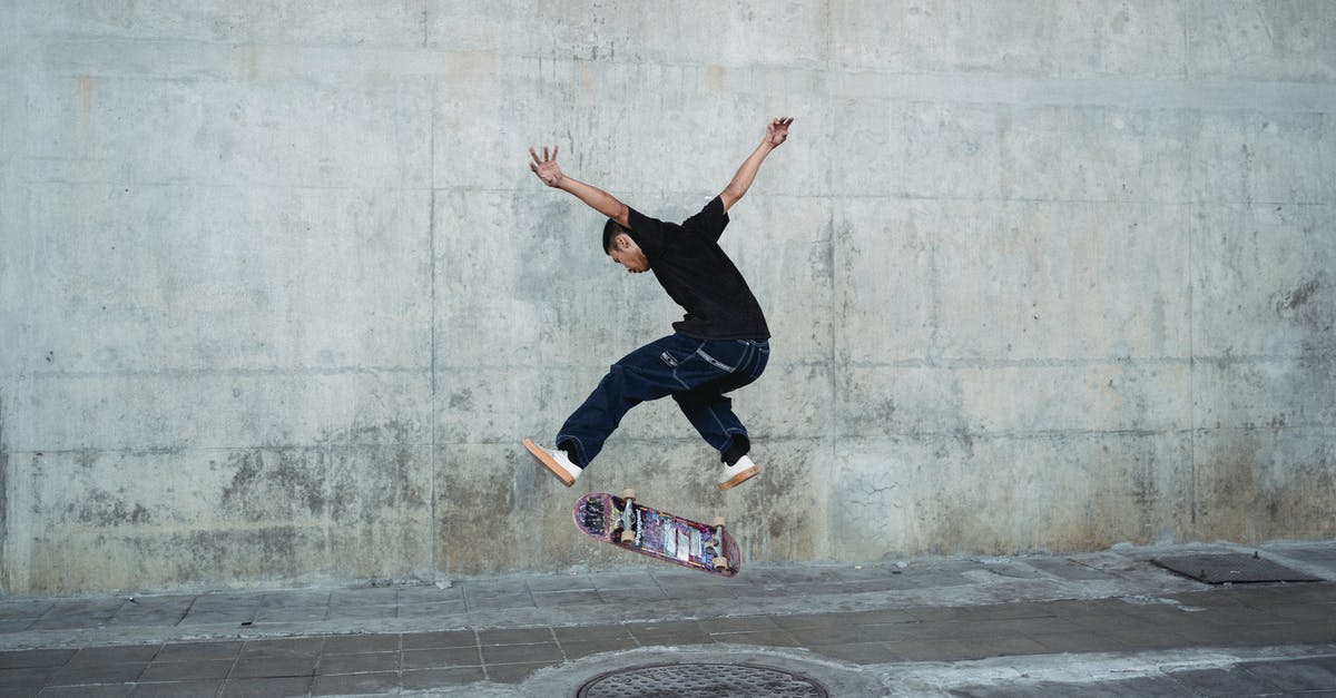 Rajesh suddenly gets over his hesistation? - Young man jumping with skateboard above manhole near concrete wall