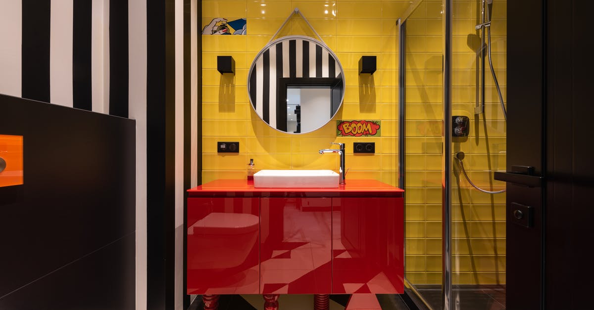 Red Sparrow shower scene - Interior of modern bathroom with sink on red cabinet near tap and mirror hanging on yellow wall near toilet and shower