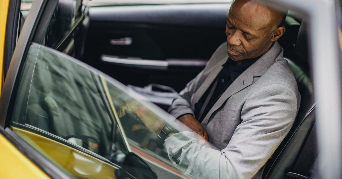 Riggan arriving in cab at the theater - Side view punctual adult African American businessman in formal clothing sitting in taxi car and checking time on wristwatch