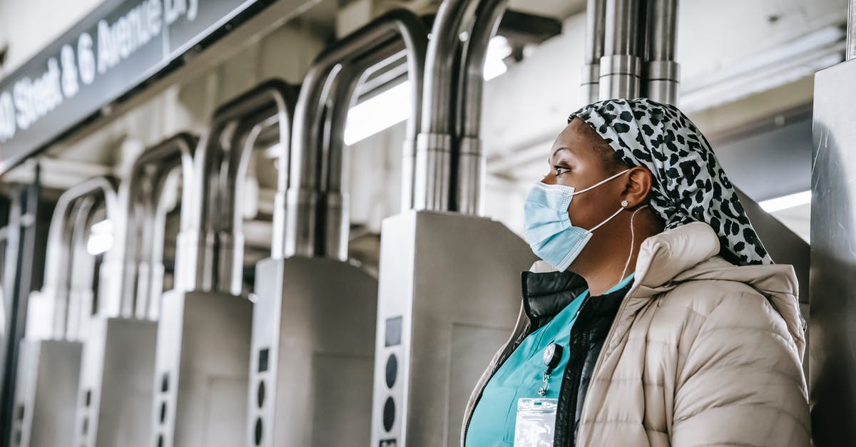 Season 5: Why does Nurse Jackie keep calling Charlie? - Side view emotionless African American female doctor wearing warm clothes and protective face mask passing through turnstile gates in New York underground