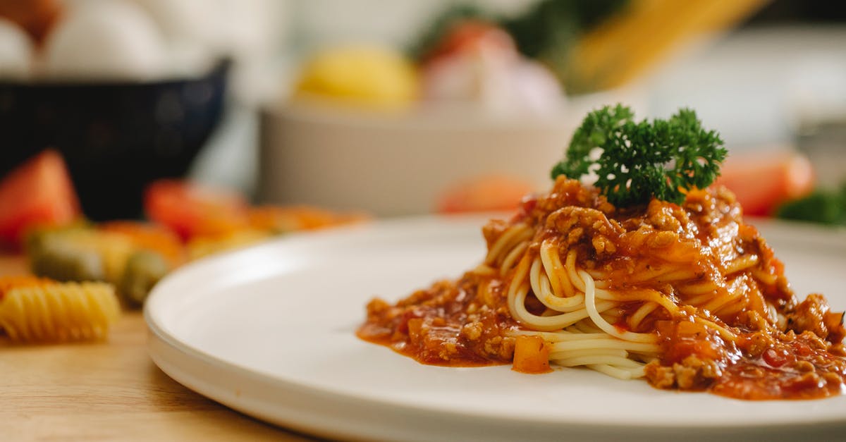 Sergio Leone's Spaghetti Westerns: English or Italian? - Delicious yummy spaghetti pasta with Bolognese sauce garnished with parsley and served on table in light kitchen
