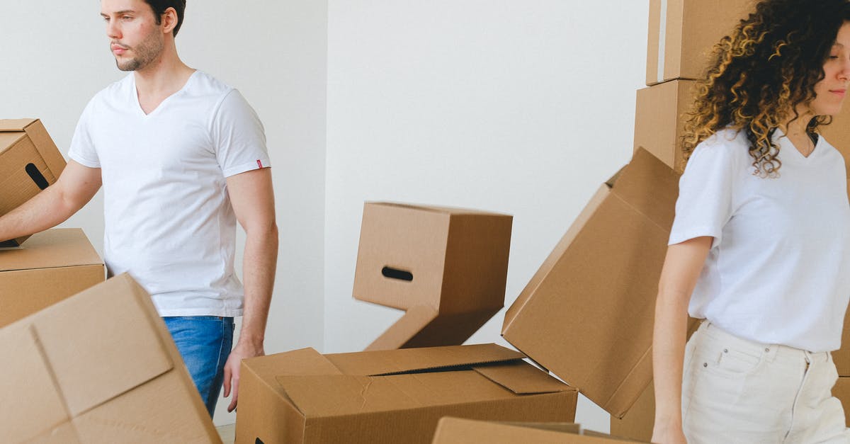 Shouldn't Ben have left the rented room in Berkeley after Elaine screamed in it and the landlord found out? - Serious young man and woman in white t shirts carrying carton boxes in light room while moving into new apartment together