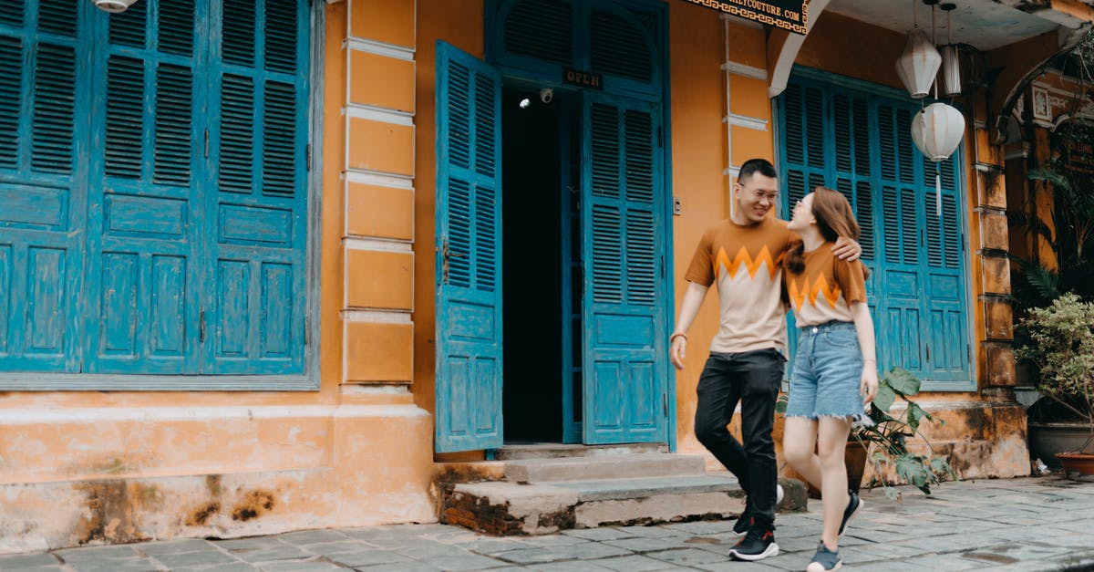 Shouldn't the building keep its same weight? [duplicate] - Full length of happy Asian couple in same t shirts hugging and looking at each other while walking on street near entrance of colorful building