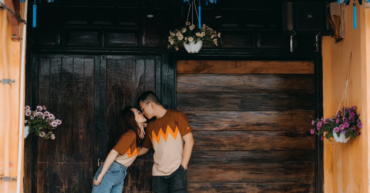 Shouldn't the building keep its same weight? [duplicate] - Romantic Asian couple kissing near wooden wall