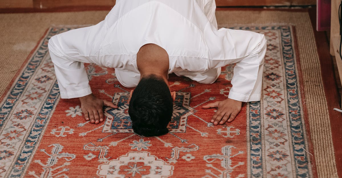 Significance of Room 203 - Man in White Thobe Bowing Down on Red and Blue Rug