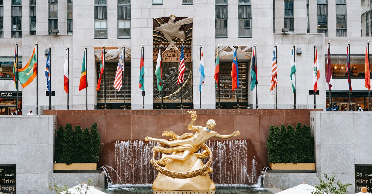 The ending in Prometheus - Golden Prometheus statue located near entrance of Rockefeller center with flags on street in New York city in modern district