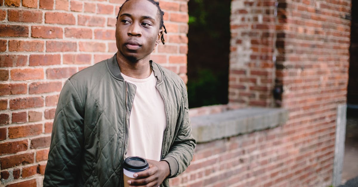 Tony Soprano calls himself a soldier and argues that means he won't go to hell -- does he really think that? - Young African American male in casual wear with coffee to go standing near red brick wall and looking away while waiting for friend
