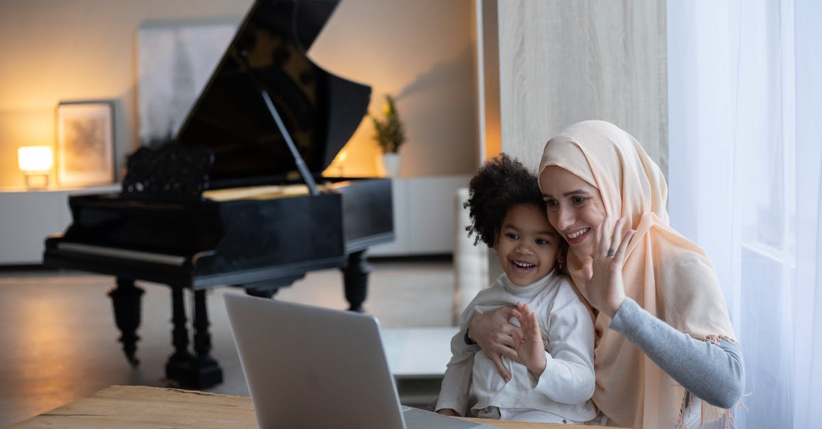 Two foster kids talk (as captives) through an air duct between their rooms? [closed] - Positive Muslim mother and adorable African American girl sitting at table near window and having video call on portable laptop