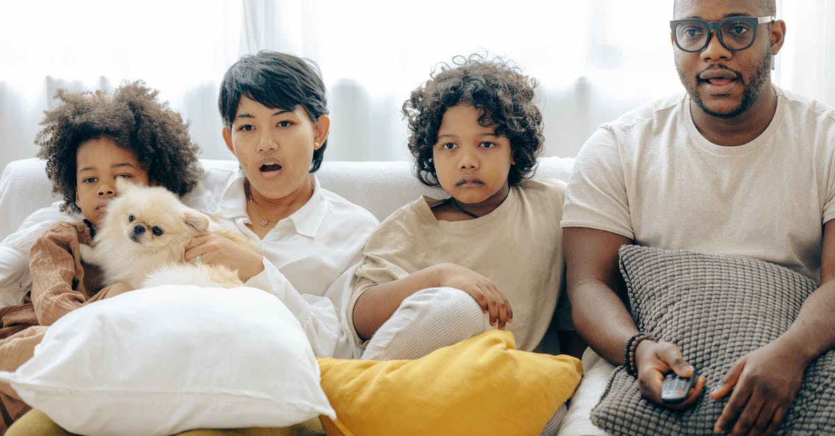 Use of anachronisms in film intros to surprise the user with the revelation of the actual time period - Interested multiracial family watching TV on sofa together with dog