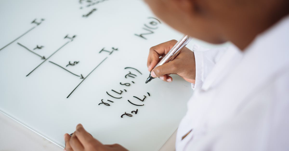 Use of capital letters in credits - From above anonymous ethnic student wearing uniform and solving problem in chemistry while writing formula on white table in lab