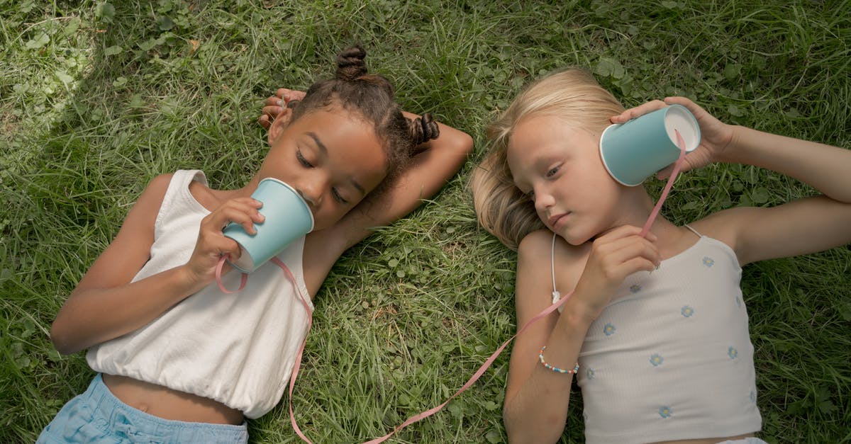 Using two wands at a time in Harry Potter - Two Teenage Girls Laying on Grass and Playing Telephone Call Using Paper Cups on String