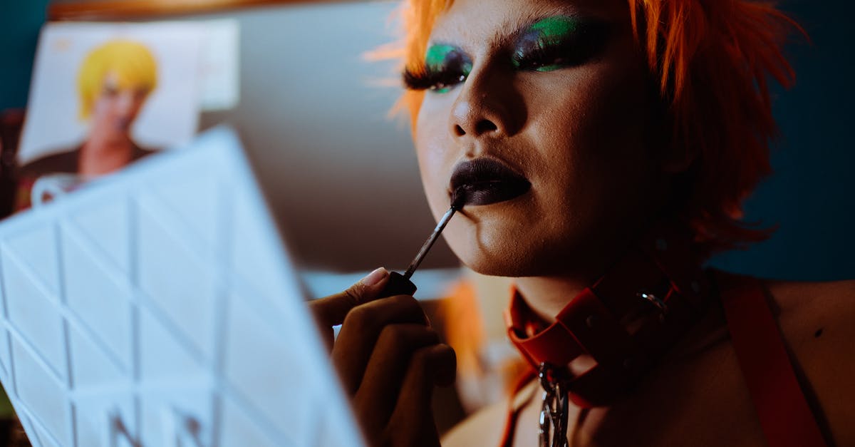 Was Bugs Bunny a gay character? - Low angle of crop ethnic eccentric transgender guy with bright makeup in wig and leather collar applying dark lipstick while preparing for performance in nightclub