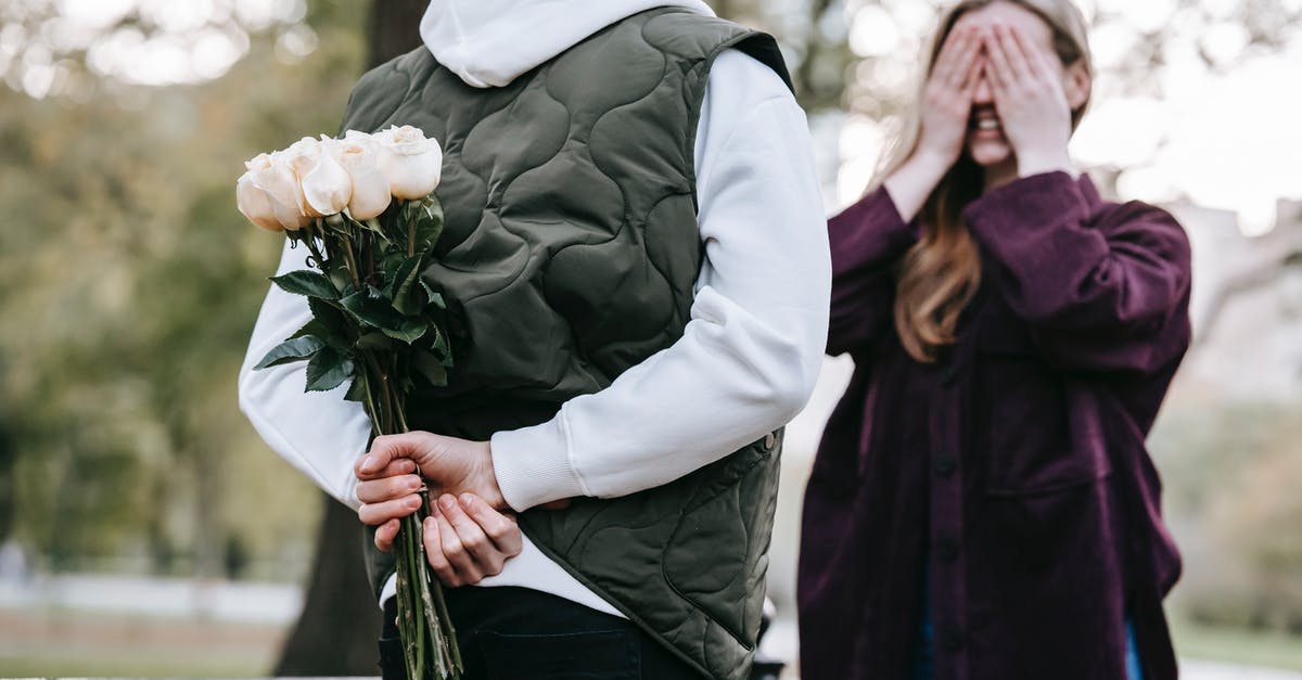 Was it normal for Ali Rose to hide cash in their house? - Crop unrecognizable man in warm clothes going to give bouquet of roses as surprise gift to happy girlfriend covering eyes with hands in park