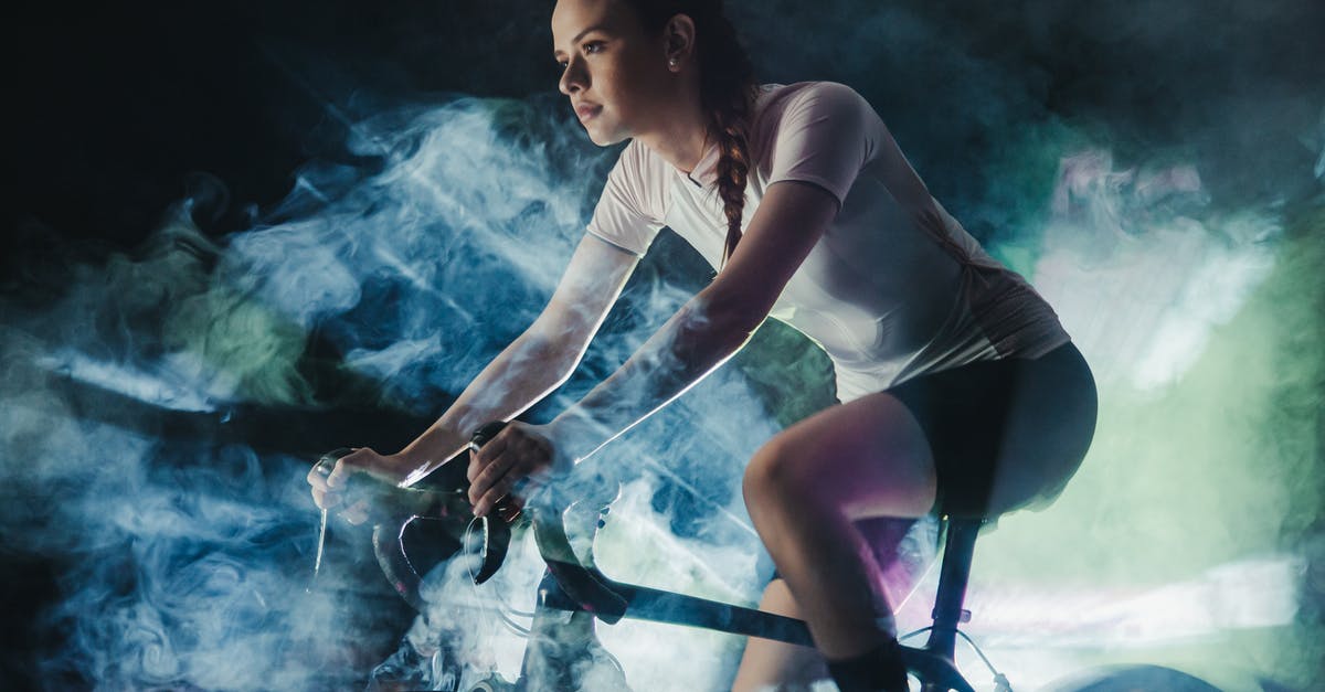 Was the smoke in this scene accidental or a practical effect serving to depict something? - Young female athlete in active wear with concentrated gaze riding bicycle in shiny cloud while looking forward