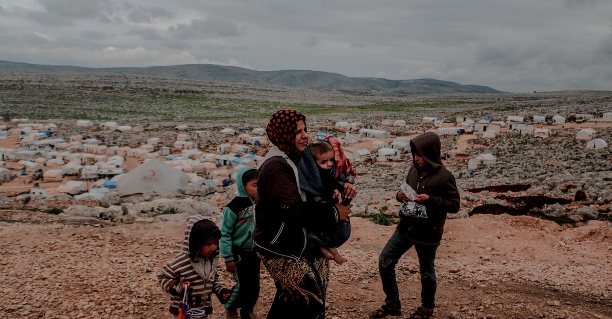 Was the War Boy language ever codified? - Poor ethnic woman with toddler in arms and kids near settlement surrounded with mountains under cloudy gloomy sky