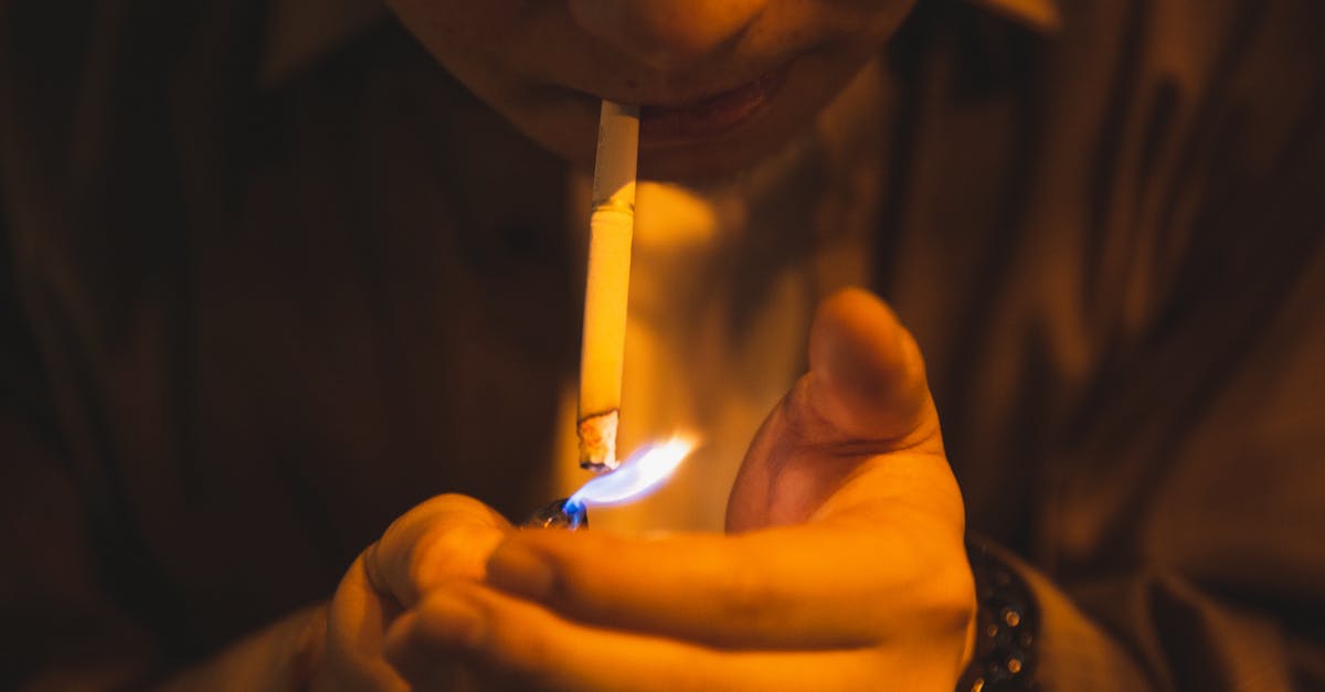 Was there ever noticeable criticism about Breaking Bad possibly glorifying the drug business? - Crop male with burning lighter and cigarette smoking for reducing stress in light of lamp