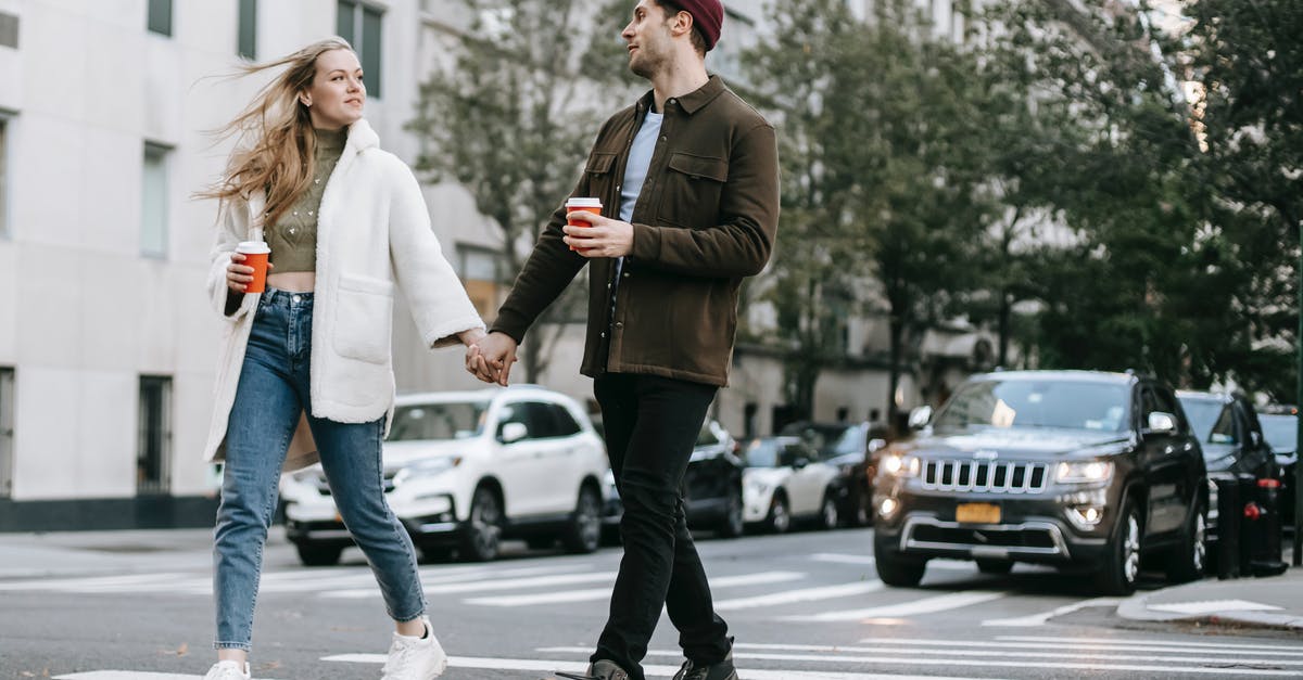 What's going on with 2 Majors mirroring each other? - Young couple wearing warm jackets and with paper cups of hot drinks crossing road holding hands and looking at each other